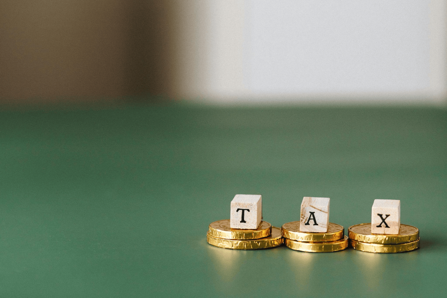 Letter cubes are spelling out TAX and are placed on top of coins